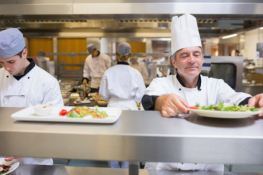 Head chef checking salad in the kitchen before service